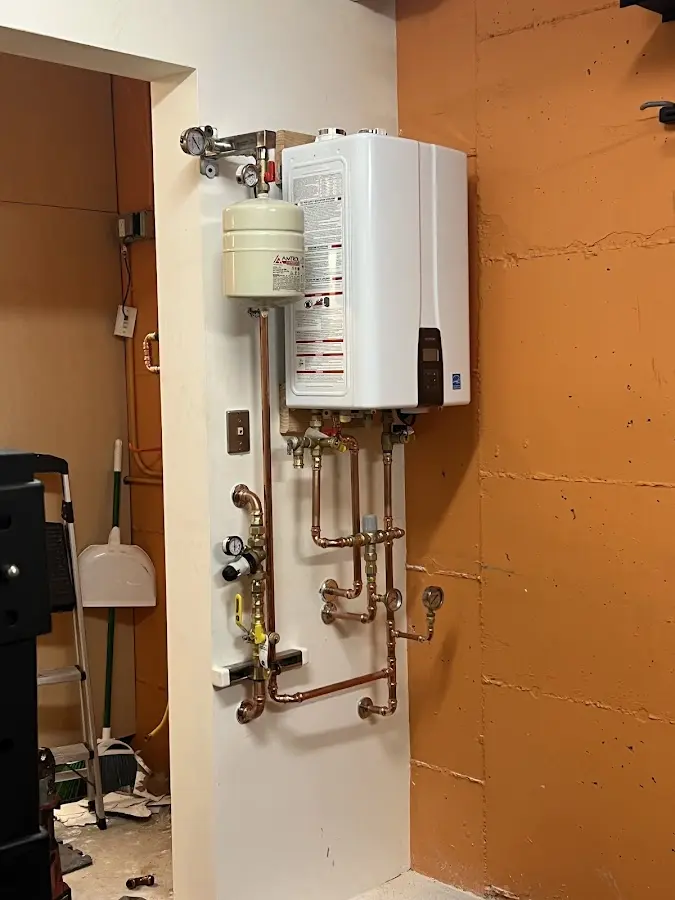 Plumbing technician inspecting water heater connections in Gibson